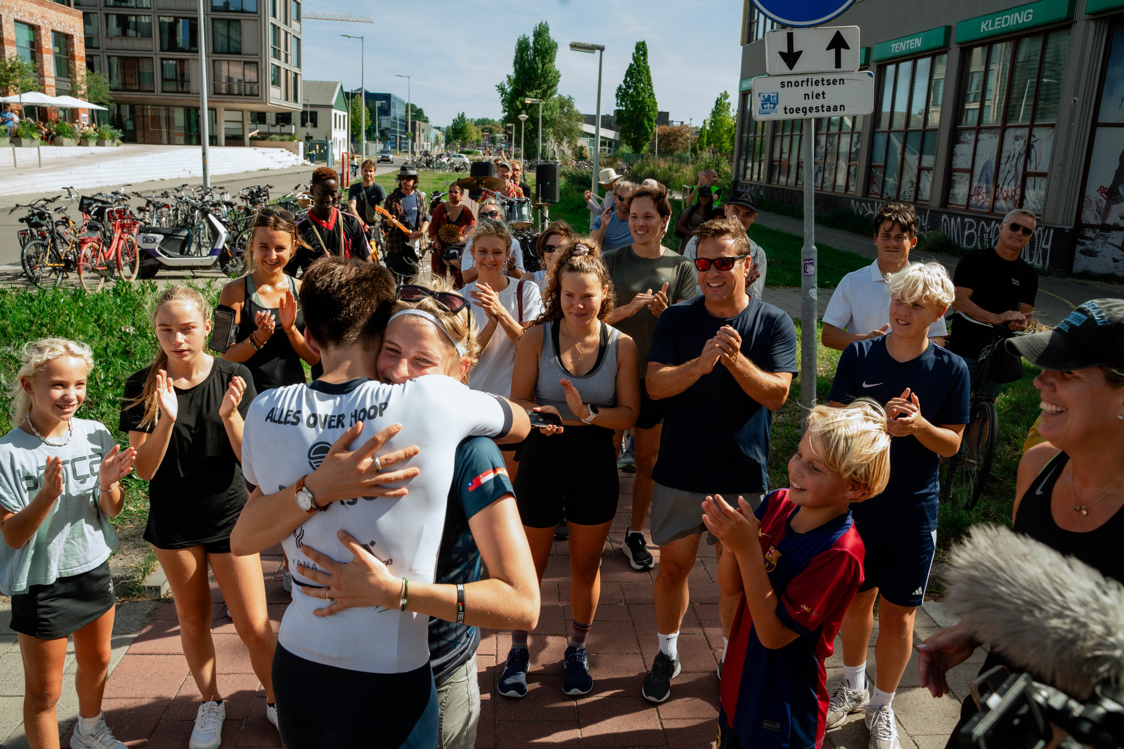Een emotionele omhelzing bij de finish, omringd door een juichende menigte